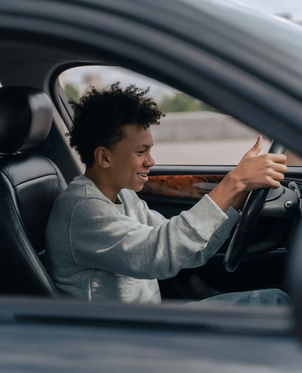 Jeune élève souriant au volant pendant une leçon de conduite WorldofBiz